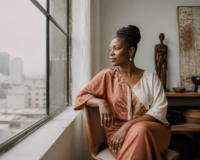 Femme entrepreneure diaspora africaine réfléchissant à sa stratégie d'investissement dans un bureau élégant à Kinshasa.