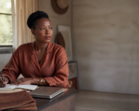 Maman entrepreneure Afrique travaillant dans un studio élégant à Kinshasa, illustrant la conciliation business et famille.