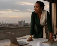 Entrepreneure congolaise travaillant sur son pitch deck dans un studio à Kinshasa, lumière de fin de journée.